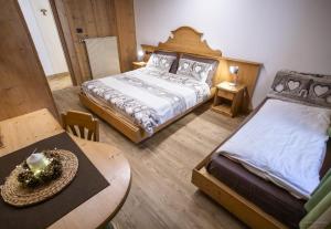a bedroom with two beds and a table and a table sidx sidx sidx at Appartamenti dei Maerins in Pozza di Fassa