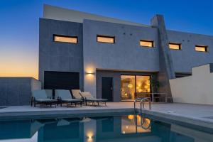 a house with a swimming pool next to a building at VillasRoyale Rex - no steps, easy access, heated pool & BBQ in Meloneras