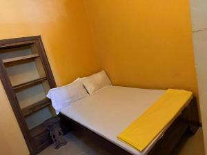 a small bed in a room with a yellow wall at Utu house in Zanzibar City