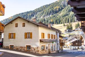 a building on a street with a mountain in the background at Appartamenti dei Maerins in Pozza di Fassa