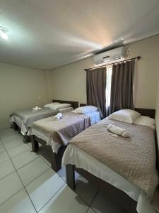 a room with three beds and a window at HOTEL SAYMON - Cafelândia PARANÁ in Cafelândia
