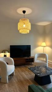 a living room with two chairs and a flat screen tv at Appartement Jehan de Beauce in Chartres