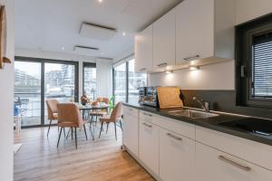 a kitchen with white cabinets and a table with chairs at Houseboat-Oostende in Ostend