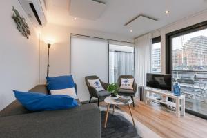 a living room with a couch and chairs and a tv at Houseboat-Oostende in Ostend