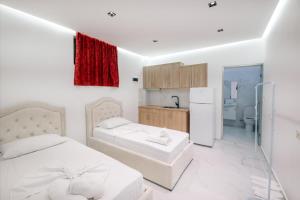 a white bedroom with two beds and a refrigerator at Vila Myrtaj in Ksamil