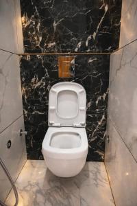 a bathroom with a toilet with a black marble wall at Hotel Mariott Inn in Prayagraj