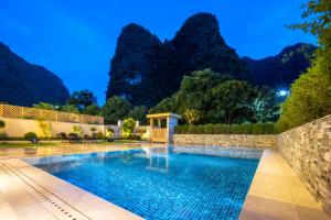 a swimming pool with mountains in the background at Yangshuo Xishan Resort in Yangshuo +86 photos