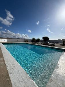 a swimming pool with blue water in front of a building at El aceitunal private pool in Puerto del Rosario