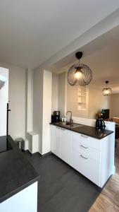a kitchen with white cabinets and a black counter top at Appartement Jehan de Beauce in Chartres