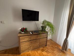 a living room with a dresser with a tv on the wall at Apartman Amal II in Vukovar