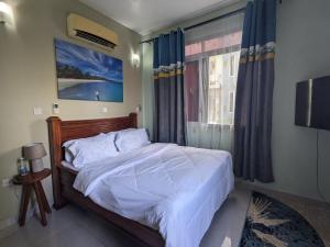 a bedroom with a bed and a window with blue curtains at Zanzi modern 2 bed apartment GF in Zanzibar City