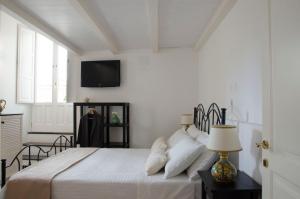 a bedroom with a bed with a tv on the wall at Casa Camelia - Cathedral View Apartment, 90m from Duomo in Noto