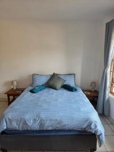 a bed with a blue comforter in a bedroom at Driftwood Haven in Mossel Bay +4 photos