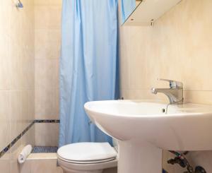 a bathroom with a sink and a toilet and a blue shower curtain at Sirius in La Isleta del Moro