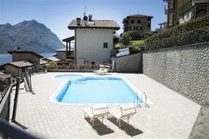 a swimming pool with two chairs and a wall at IseoLakeRental - Casa Lani in Costa Volpino