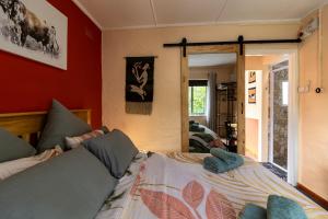 a bedroom with a bed and a red wall at Birdsong Cottage in Howick