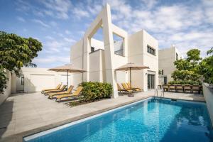 a white house with a swimming pool and chairs at VillasRoyale Trespalomas - An Iconic Villa for Elevated Getaways! in Meloneras