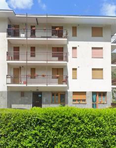 a white apartment building with balconies and a hedge at Casa Pioda in Chiomonte