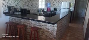 a kitchen with a counter with stools and a refrigerator at Aconchego das Araras in Sirinhaém