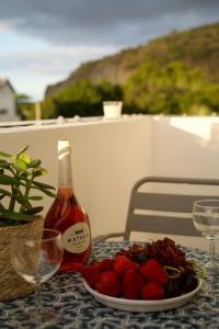 a bottle of wine and a plate of strawberries on a table at Le Frangipanier in La Possession