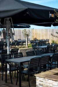a group of tables and chairs under a black umbrella at The Oakwood Hotel in Gloucester +44 photos