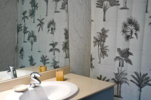 a bathroom with a sink and a shower curtain with palm trees at Le Frangipanier in La Possession +16 photos