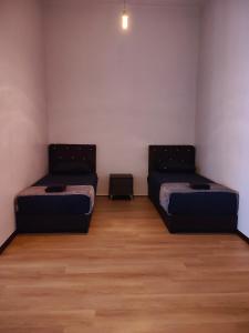 a room with two beds and a wooden floor at Kayangan Suite - Home Studio in Kangar