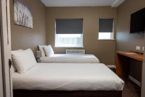two beds in a hotel room with two windows at The Oakwood Hotel in Gloucester