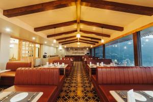 a restaurant with red chairs and tables and windows at Avira Hotel in Gangtok