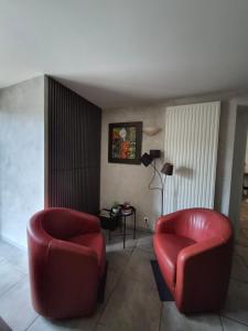 a living room with two red chairs and a table at Le lieu in Saint-Amour