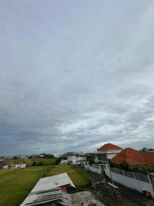 a view of a field and buildings with a cloudy sky at Agustik Villas in Badung +4 photos