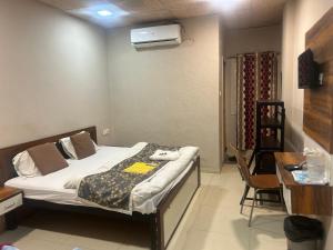 a bedroom with a bed and a desk and a table and chair at Hotel JT in Indore
