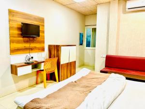 a bedroom with a bed and a desk and a tv at Hotel JT in Indore