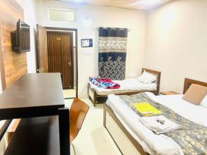 a small room with two beds and a table at Hotel JT in Indore
