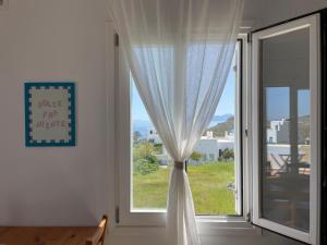 a window with a white curtain and a view of the ocean at Gaia Serifos Apartments in Rámos