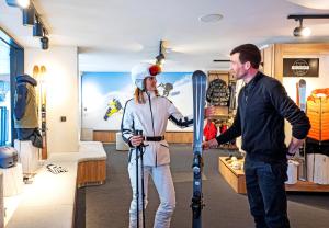 Ein Mann und eine Frau halten Skier in einem Geschäft in der Unterkunft Hôtel VoulezVous by Les Etincelles in Tignes + 50 Fotos