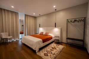 a bedroom with a bed and a chair in it at Essence Villas - Garden & Spa in Ribeira Grande