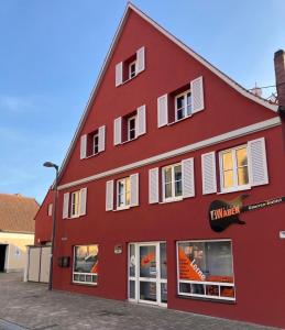 a red building with white shuttered windows at Ferienwohnung Raabenhorst in Oettingen in Bayern