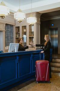 two women standing at a counter with a red suitcase at Hotel Cristal Park in Tarnów