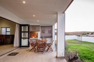 a dining room with a table and chairs on a patio at Sea Spray Self Catering in Duyker Eiland in Britannia Bay