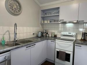 a white kitchen with a sink and a stove at Daisy Cottage on Duke 1BR in Yarram +9 photos