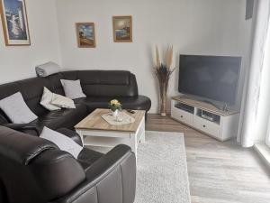 a living room with a black leather couch and a television at Wohnung Jolmes in Dahme