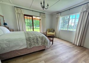 a bedroom with a bed and a chair and windows at Scafell homestead, Cobham, Himeville in Ixopo