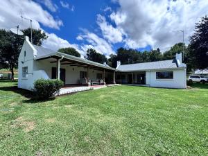 a white house with a large yard at Scafell homestead, Cobham, Himeville in Ixopo