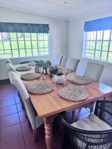 a wooden table with chairs and plates on it at Scafell homestead, Cobham, Himeville in Ixopo
