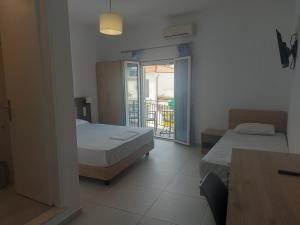 a hotel room with two beds and a balcony at Karafelas rooms in Skiathos