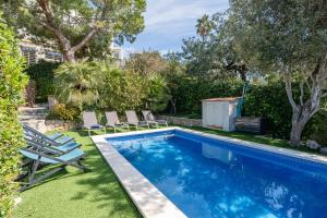 a swimming pool with chairs and a yard at Villa Les Moreres de Sitges in Sitges