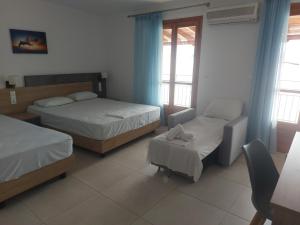 a hotel room with two beds and a chair at Karafelas rooms in Skiathos +10 photos