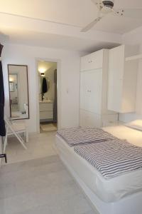 a white bedroom with a bed and a mirror at Villa D - Kamari Village in Aliko Beach