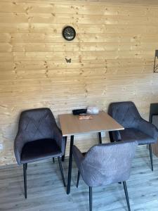 a table with two chairs and a clock on a wall at maringotky Šumava in Dlouhá Ves +1 photo